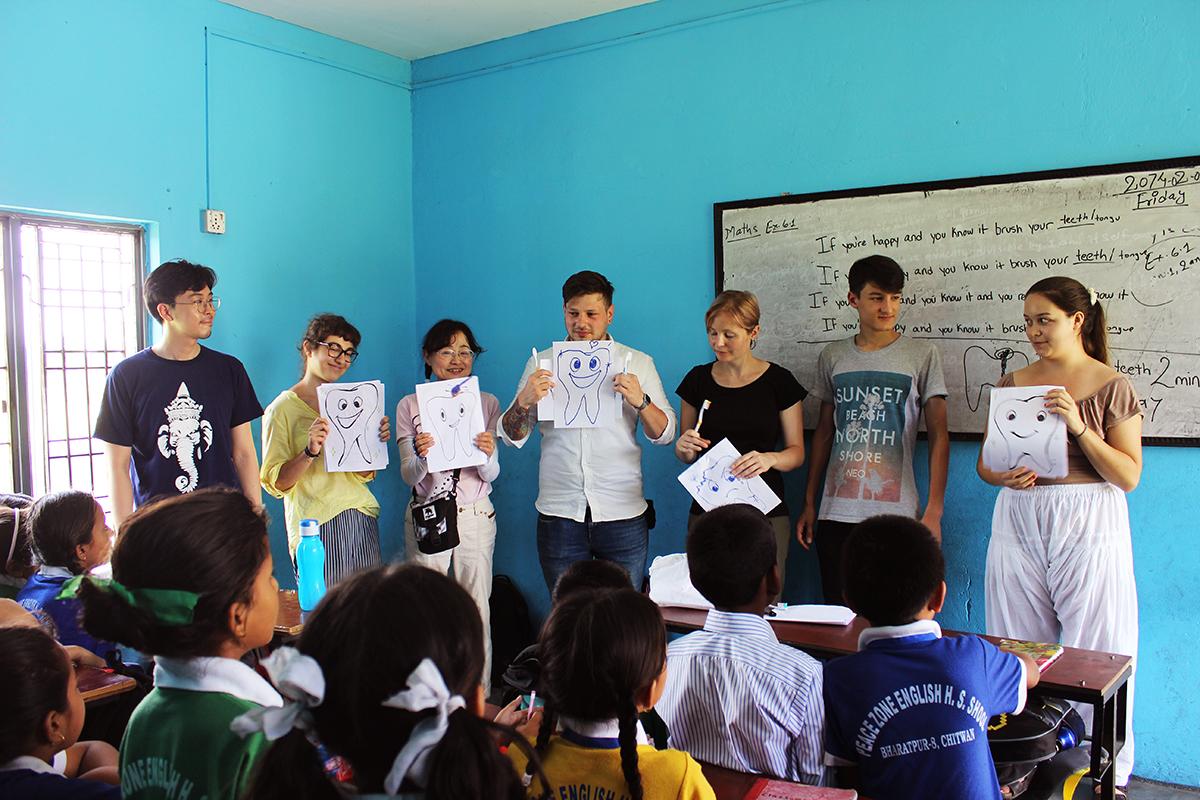 A group of medical interns teach children about oral hygiene at a school in Nepal. A group doing medical internships in Nepal help teach young children about oral hygiene at a local school.